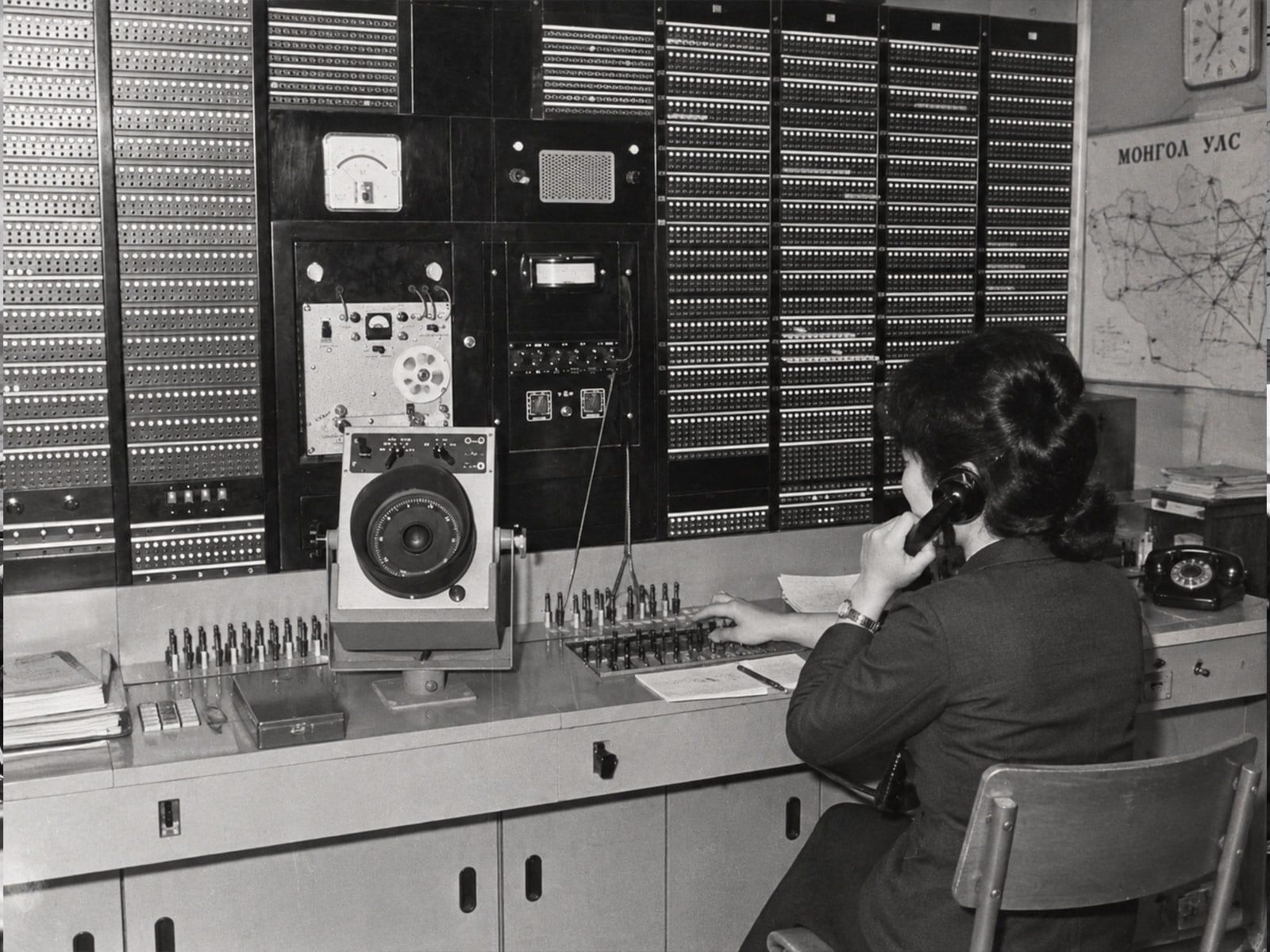 An operator at a long-distance switching console, with a map of Mongolia on the wall.