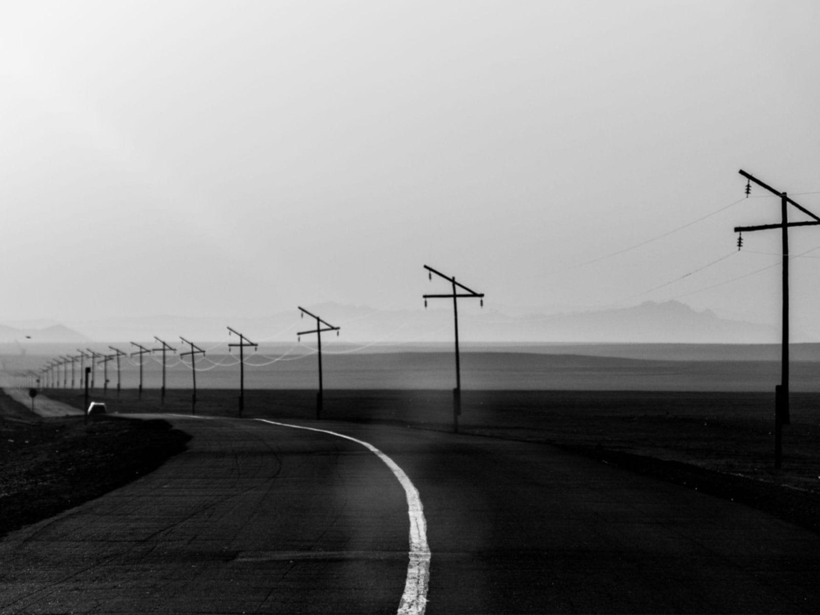 Telephone poles following a road across open country toward distant mountains.