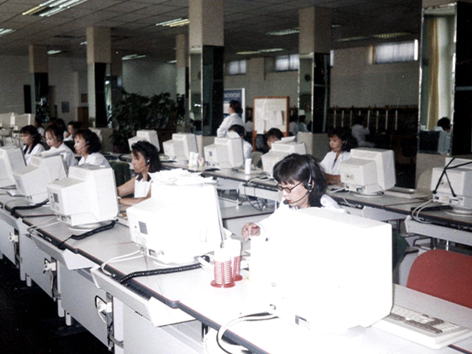 Staff wearing headsets at rows of computer terminals.