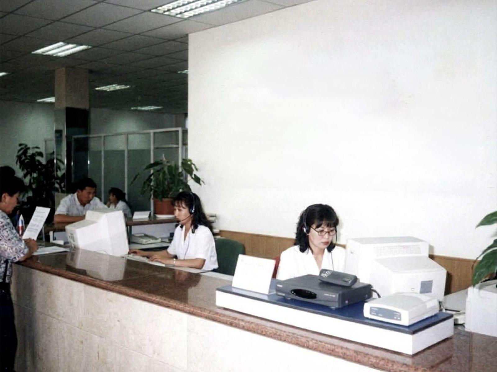 Staff at a service counter with computers and headsets.