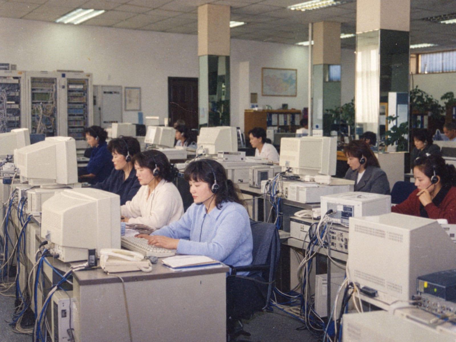 Operators wearing headsets at rows of computers.