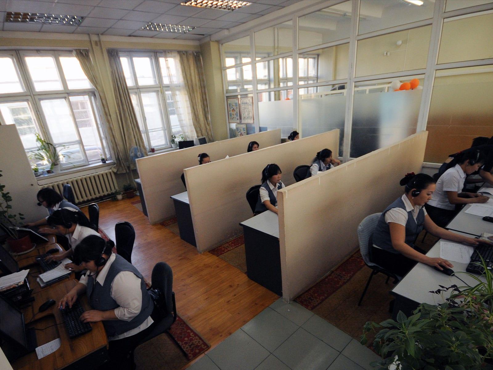 Operators wearing headsets at desks in a service office.